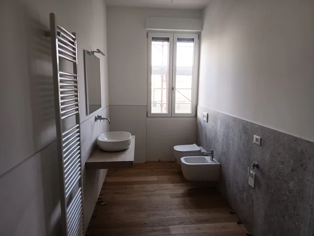 Bagno con pavimento effetto legno e termoarredo bianco