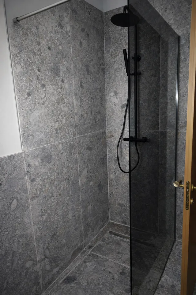 Doccia walk-in con rivestimento effetto pietra e soffione a pioggia
